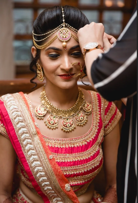 Indian bride in traditional red and gold bridal wear with matha patti